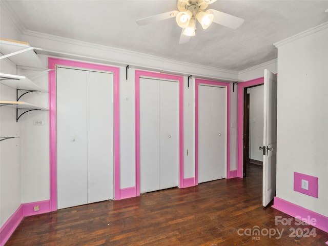 unfurnished bedroom featuring ceiling fan, ornamental molding, dark wood-type flooring, and two closets