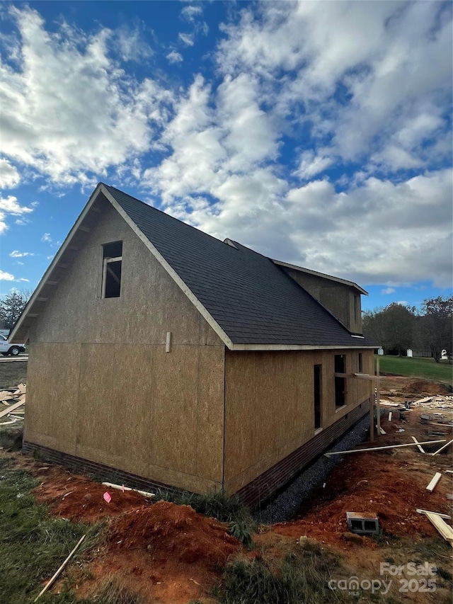 view of side of property featuring stucco siding and roof with shingles