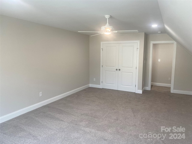 unfurnished bedroom with carpet floors, a closet, vaulted ceiling, and ceiling fan