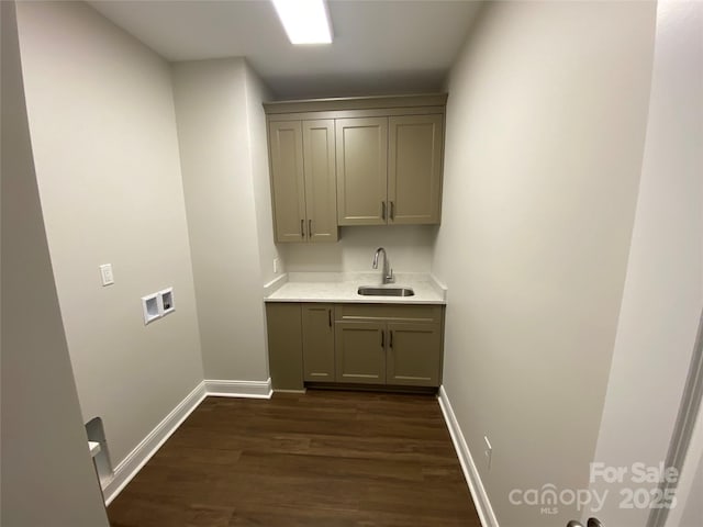 washroom featuring dark wood-type flooring, washer hookup, a sink, and baseboards