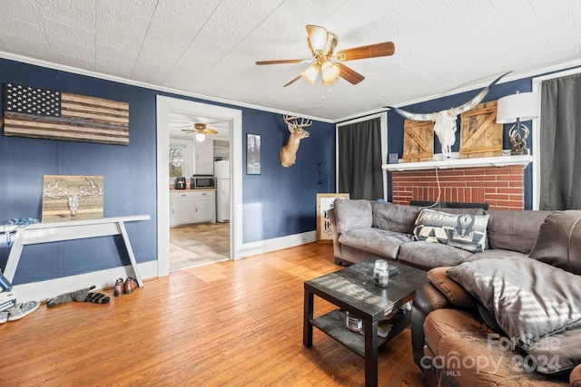 living room with ceiling fan, a fireplace, wood-type flooring, and ornamental molding