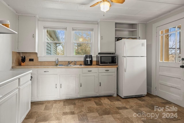 kitchen featuring crown molding, sink, white cabinets, and white refrigerator