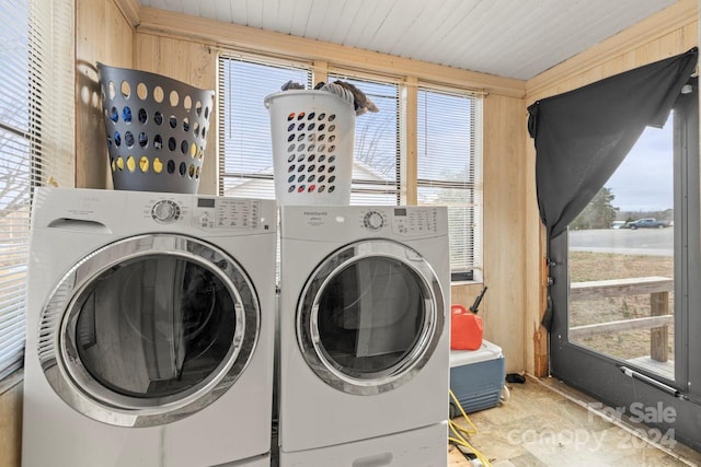 laundry area with wood walls and washer and clothes dryer