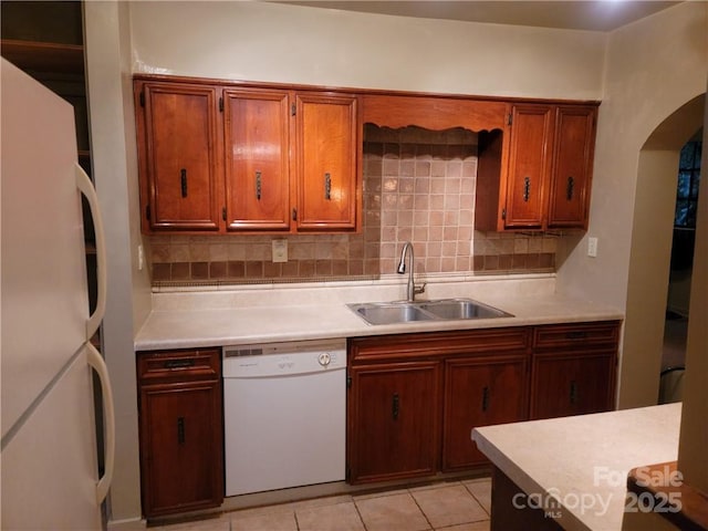 kitchen featuring light tile patterned floors, white appliances, backsplash, and sink