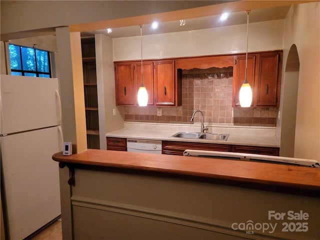 kitchen featuring tasteful backsplash, sink, pendant lighting, and white appliances