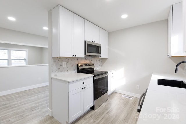 kitchen featuring white cabinets, appliances with stainless steel finishes, light wood-type flooring, and sink