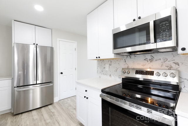 kitchen with tasteful backsplash, white cabinetry, light wood-type flooring, and appliances with stainless steel finishes