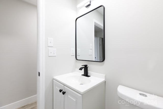 bathroom with hardwood / wood-style floors, vanity, and toilet