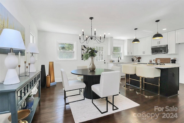 dining space with sink, dark wood-type flooring, and an inviting chandelier