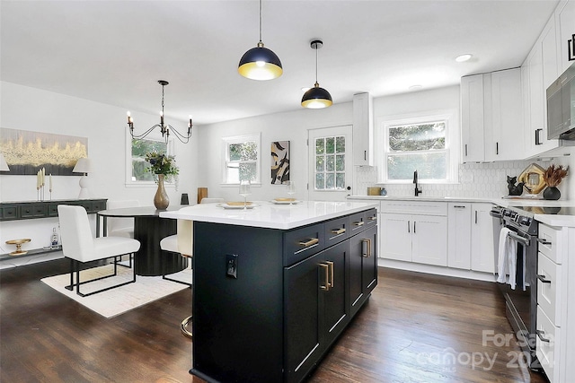 kitchen featuring pendant lighting, dark hardwood / wood-style flooring, white cabinets, and stainless steel appliances