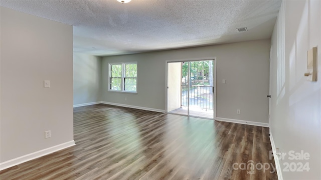 empty room with dark hardwood / wood-style floors and a textured ceiling