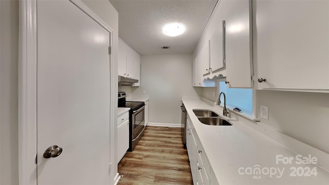 kitchen featuring sink, light hardwood / wood-style flooring, a textured ceiling, white cabinets, and appliances with stainless steel finishes