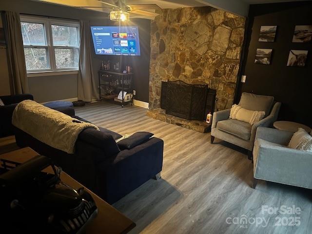 living room with hardwood / wood-style flooring and a stone fireplace