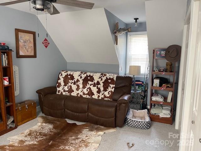 living room with ceiling fan, carpet flooring, and vaulted ceiling