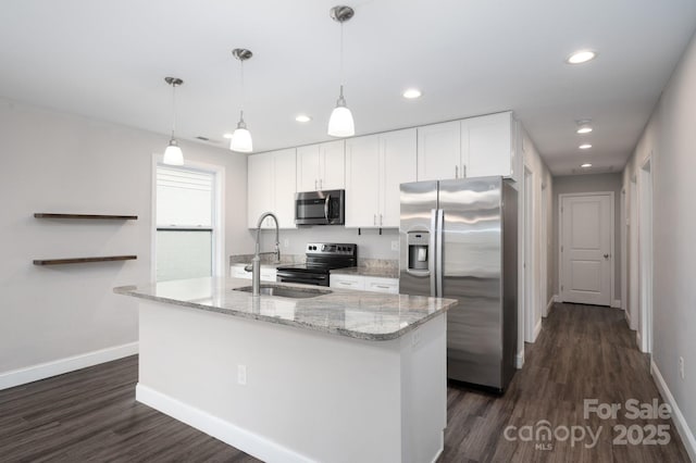 kitchen with light stone countertops, stainless steel appliances, a kitchen island with sink, sink, and white cabinets