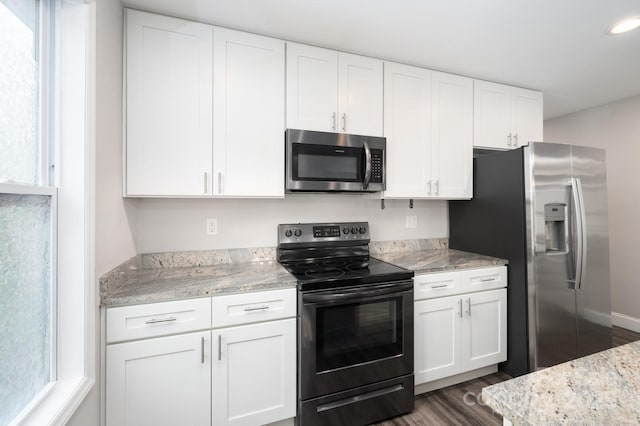 kitchen featuring light stone counters, dark hardwood / wood-style flooring, white cabinets, and stainless steel appliances