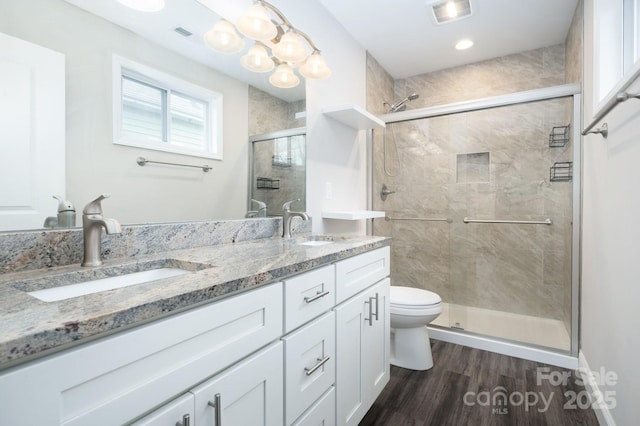 bathroom with hardwood / wood-style floors, vanity, toilet, and an enclosed shower