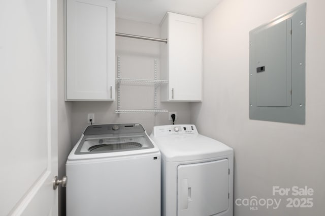 laundry room with washing machine and clothes dryer, electric panel, and cabinets