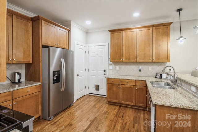 kitchen featuring sink, stainless steel refrigerator with ice dispenser, hardwood / wood-style flooring, tasteful backsplash, and decorative light fixtures