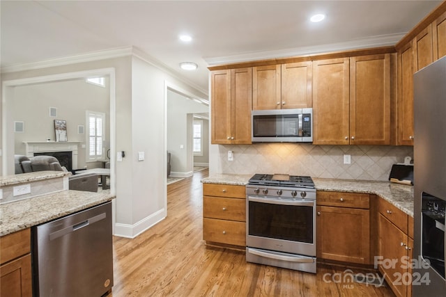 kitchen with tasteful backsplash, light stone countertops, light hardwood / wood-style flooring, and stainless steel appliances