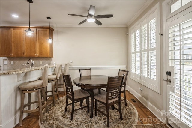 dining space featuring dark hardwood / wood-style floors, ceiling fan, ornamental molding, and sink