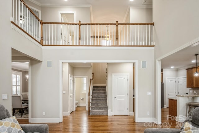 living room with wood-type flooring, crown molding, and a high ceiling