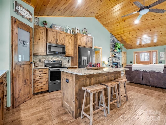 kitchen with wooden ceiling, an island with sink, light wood-type flooring, and appliances with stainless steel finishes