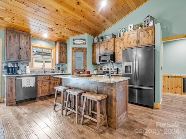 kitchen with wooden ceiling, a kitchen breakfast bar, light hardwood / wood-style floors, a kitchen island, and appliances with stainless steel finishes