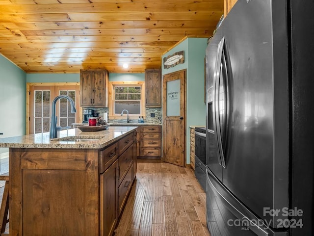 kitchen featuring sink, a center island, backsplash, light hardwood / wood-style floors, and appliances with stainless steel finishes