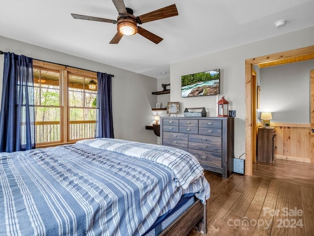 bedroom featuring dark hardwood / wood-style flooring, ceiling fan, and wooden walls