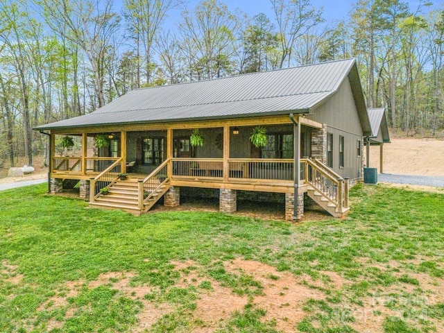 view of front of house with a front yard, cooling unit, and covered porch