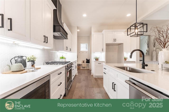 kitchen with white cabinets, sink, dark hardwood / wood-style floors, appliances with stainless steel finishes, and decorative light fixtures