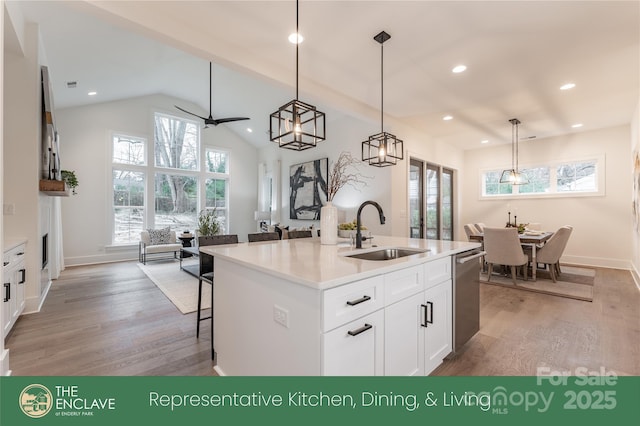 kitchen featuring white cabinetry, sink, hanging light fixtures, stainless steel dishwasher, and a kitchen island with sink