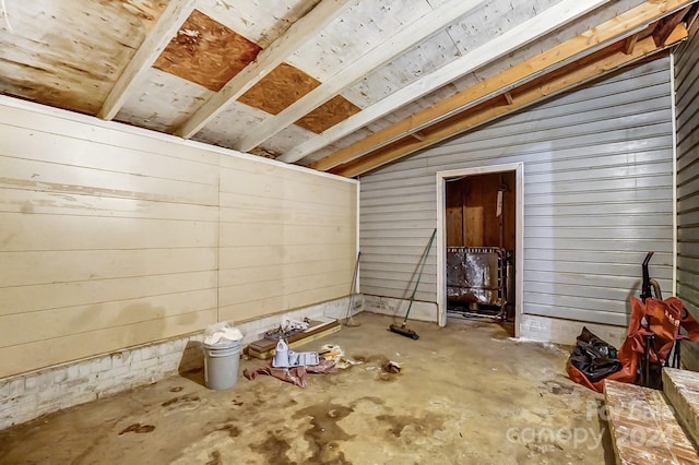 interior space with wooden walls, concrete flooring, and lofted ceiling