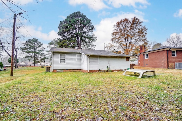 rear view of house with central air condition unit and a lawn