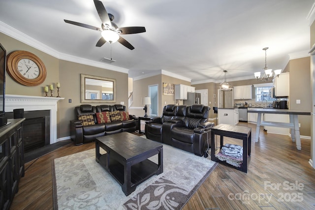 living room with hardwood / wood-style floors, crown molding, and ceiling fan with notable chandelier