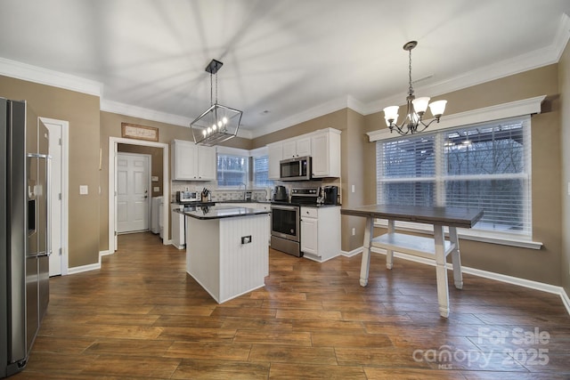 kitchen with white cabinetry, appliances with stainless steel finishes, an inviting chandelier, and pendant lighting