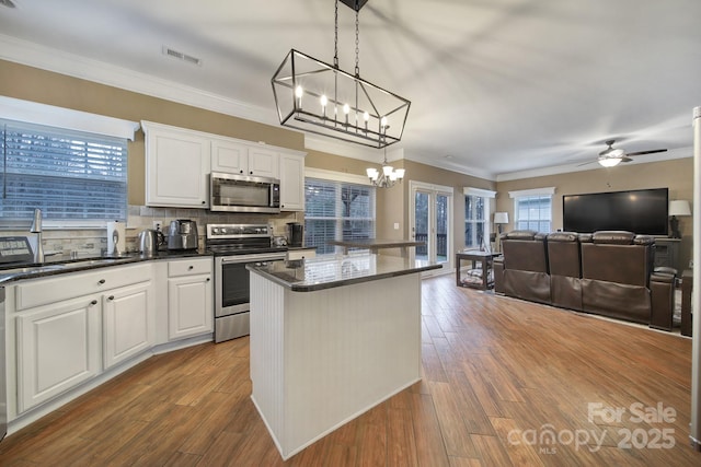 kitchen featuring pendant lighting, white cabinetry, sink, a center island, and stainless steel appliances