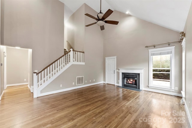 unfurnished living room featuring hardwood / wood-style flooring, ceiling fan, and high vaulted ceiling