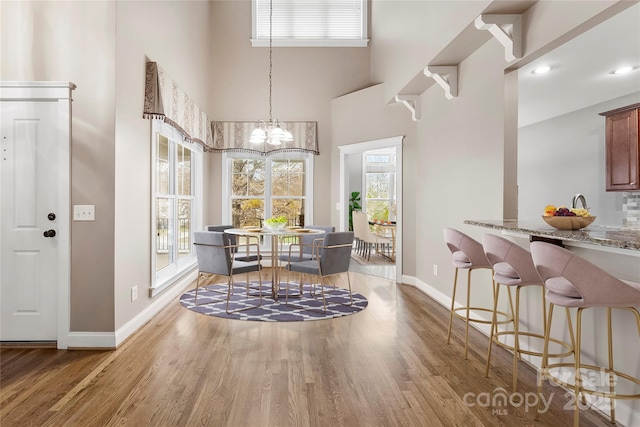 dining area with baseboards, a chandelier, and wood finished floors