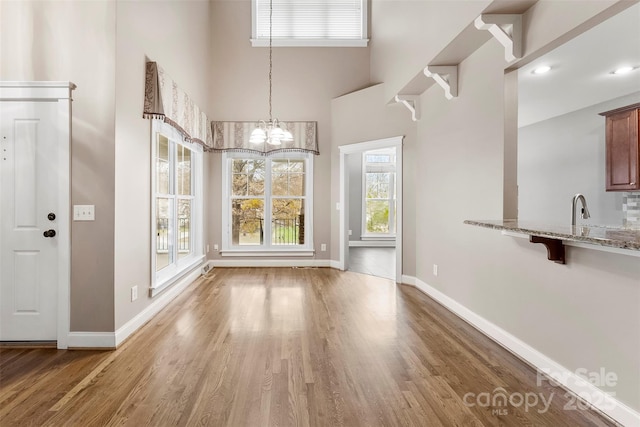 unfurnished dining area with light wood-style floors, baseboards, and a sink