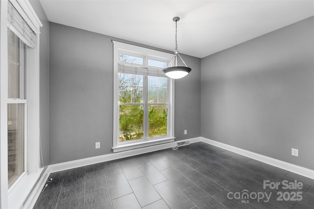 unfurnished dining area featuring dark wood finished floors and baseboards