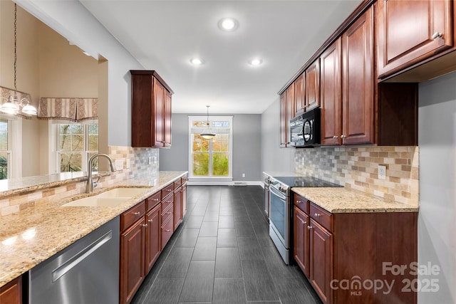 kitchen with appliances with stainless steel finishes, light stone counters, a sink, and pendant lighting