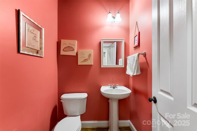 bathroom with toilet, baseboards, and a sink