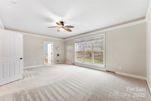 spare room with baseboards, carpet flooring, visible vents, and crown molding