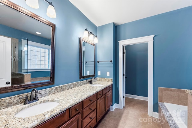 bathroom with tiled bath, baseboards, a sink, and tile patterned floors