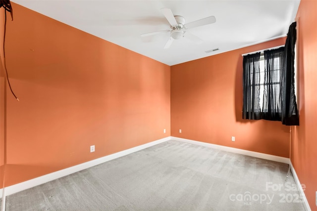 carpeted spare room featuring ceiling fan, visible vents, and baseboards