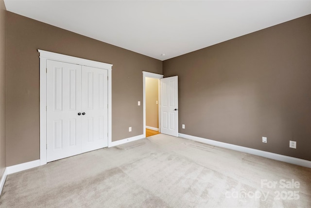 unfurnished bedroom featuring light carpet, a closet, and baseboards