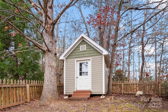 view of outdoor structure featuring entry steps, fence, and an outbuilding