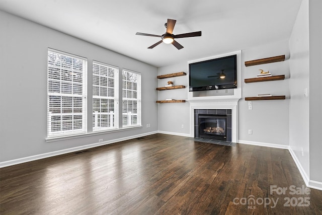 unfurnished living room featuring ceiling fan, dark wood-type flooring, and a fireplace